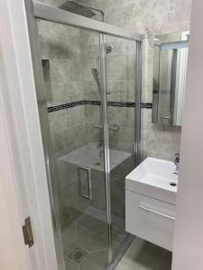 a shower with a glass door next to a sink at Lovely en-suite studio with kitchen and free parking with walking distance to tube station and short train ride to central London!! in Northwood