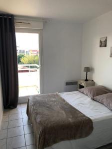 une chambre avec deux lits et une grande fenêtre dans l'établissement Côté Bassin, à Arcachon