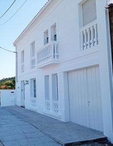 a white building with two garage doors and a balcony at Casa Amelia 1ªP a 50 m Camino de Santiago in Padrón