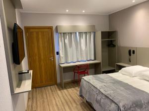 - une chambre avec un lit, un bureau et une fenêtre dans l'établissement Hotel Villa Inácia, à Vacaria