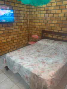 een slaapkamer met een bed en een bakstenen muur bij Cifa & Alê Hospedaria in Conde