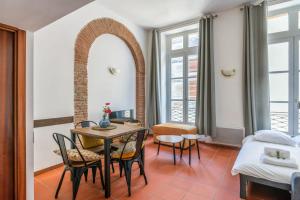a room with a table and chairs and a bed at Very nice duplex located on the main square - Toulouse - Welkeys in Toulouse