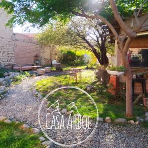 un patio trasero con un jardín con una mesa y un árbol en Casa Arbol Domos en Cafayate