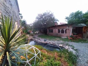a garden with a creek next to a building at Casa Arbol Domos in Cafayate