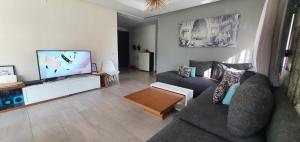 a living room with two couches and a flat screen tv at Appartement luxe Taghazout bay - mer & piscine in Agadir