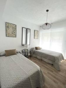 sypialnia z 2 łóżkami i żyrandolem w obiekcie Apartamento céntrico y en primera línea de playa w mieście Benidorm