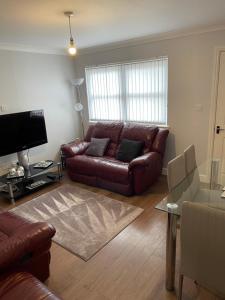 a living room with a brown leather couch and a television at Fife Apartments in Dunfermline