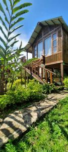 uma casa de madeira com uma pessoa de pé num deque em La Guarida eco-posada em San Antonio del Tequendama