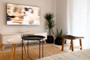 uma sala de estar com uma televisão e uma mesa e cadeiras em Pearl by the sea em Preveza