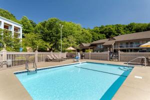 a swimming pool with a person sitting on a chair next to a house at Best Western Smoky Mountain Inn in Waynesville