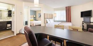 a hotel room with a desk and a room with two beds at Sonesta Simply Suites Chicago Naperville in Warrenville