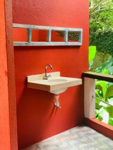un lavabo sur le côté d'une paroi rouge dans l'établissement Chales Terra Pura, à Camburi