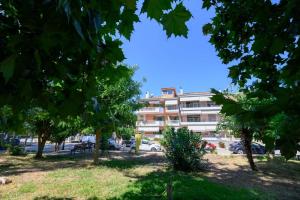 a building in a parking lot with trees in the foreground at Pearl by the sea in Preveza