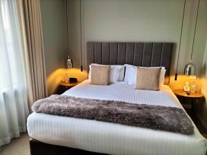 a bedroom with a large bed with a fur blanket at de Russie Boutique Hotel in Orange
