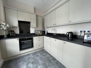 a kitchen with white cabinets and black counter tops at Grisedale Pike in Keswick