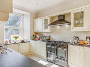 a kitchen with white cabinets and a stove top oven at Menai View in Llanfairpwllgwyngyll