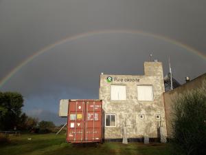 un arco iris sobre un edificio con un gran letrero de escape. en Puro Deporte entrenamiento y hospedaje en Necochea