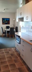 Una cocina con gabinetes blancos y una mesa con sillas. en Ohope Lifestyles, en Ohope Beach