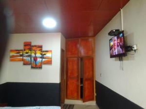 a bedroom with two paintings on the wall and a television at Sunrise Center Ngousso Yaounde in Yaoundé
