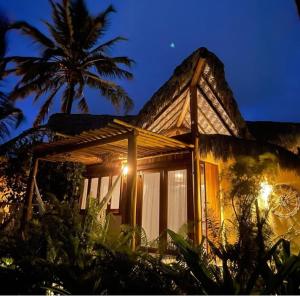 a house with a palm tree in front of it at Pousada Casa das Rendas in Praia de Moitas