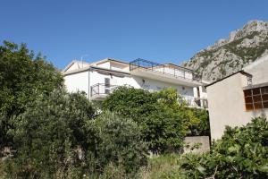 un edificio bianco con una montagna sullo sfondo di Apartments with a parking space Gradac, Makarska - 6783 a Gradac (Grado)