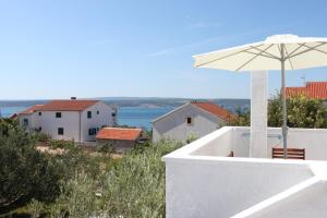 a white building with a white umbrella and the ocean at Apartments with a parking space Maslenica, Novigrad - 6548 in Jasenice