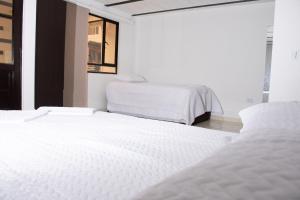 2 bedden in een kamer met witte lakens bij RAKIRA SUITES APARTAHOTEL CAMPESTRE in Ráquira