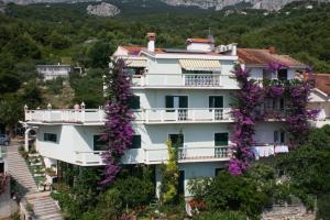 een groot wit gebouw met paarse bloemen erop bij Apartments and rooms with parking space Podgora, Makarska - 6706 in Podgora
