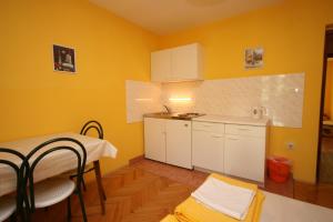 een keuken met gele muren en een tafel en stoelen bij Apartments and rooms with parking space Podgora, Makarska - 6706 in Podgora