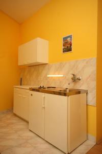 a kitchen with white cabinets and a sink and yellow walls at Apartments and rooms with parking space Podgora, Makarska - 6706 in Podgora