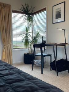 1 dormitorio con escritorio, mesa y planta en Views to unwind - self contained unit w/king bed, en Ruakaka