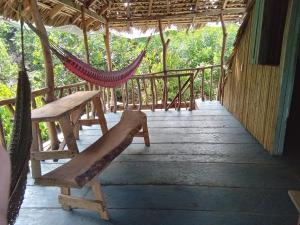 a hammock on a porch of a house at Hostel Del Lago Yojoa Backpackers in Agua Azul