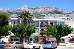 a building with cars parked in front of a mountain at Apartments by the sea Makarska - 6843 in Makarska
