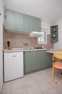 kuchnia z zielonymi szafkami i białą lodówką w obiekcie Apartments with a parking space Povljana, Pag - 6501 w mieście Povljana