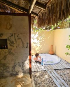 a baby sitting in a bath tub in a room at Pousada Casa das Rendas in Praia de Moitas