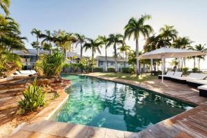 a swimming pool with palm trees in a resort at Mangrove Hotel in Broome