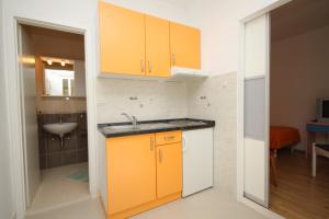una cucina con armadi arancioni e lavandino di Apartment Tucepi 6806b a Tučepi