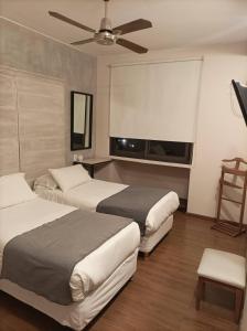 two beds in a hotel room with a flat screen tv at Hotel Internacional in Mendoza