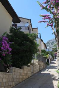 a row of houses on a street with purple flowers at Studio Podaca 6902c in Podaca