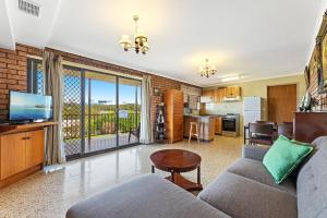a living room with a couch and a tv and a kitchen at Grandview Apartment Ocean Views in Kianga