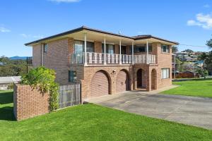 a large brick house with a balcony and grass at Grandview Apartment Ocean Views in Kianga