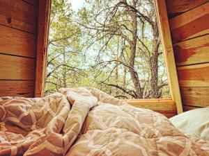 a bed in front of a window in a log cabin at Pequeña cabaña mágica con chimenea interior in Arteaga