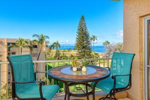 a table and chairs on a balcony with the ocean at Menehune Shores 626 in Kihei