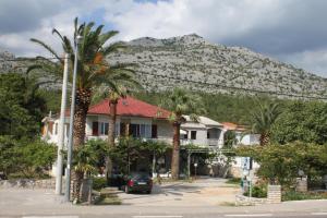 a house with palm trees in front of a mountain at Apartments by the sea Starigrad, Paklenica - 6586 in Starigrad