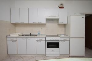 a kitchen with white cabinets and a sink and a refrigerator at Apartments by the sea Starigrad, Paklenica - 6586 in Starigrad +24 photos