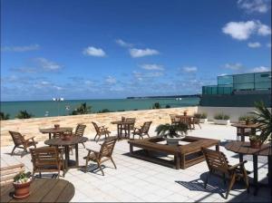 a patio with tables and chairs and the beach at Flat beira mar Tambaú in João Pessoa