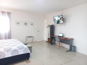 a bedroom with a bed and a desk and a computer at W's Hostel in San José