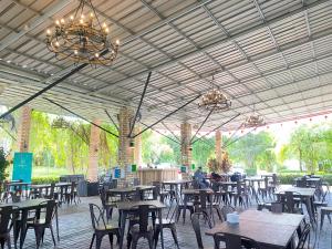 a restaurant with tables and chairs and a chandelier at "D'BAMBOO KAMP" Desa Wisata Ekang in Lagoi
