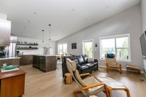a living room with a black couch and a kitchen at Amazing North Shore Estates w Private Beach in Lake Cowichan