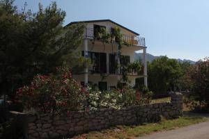 a house with a stone wall and flowers at Apartments with a parking space Starigrad, Paklenica - 6647 in Starigrad